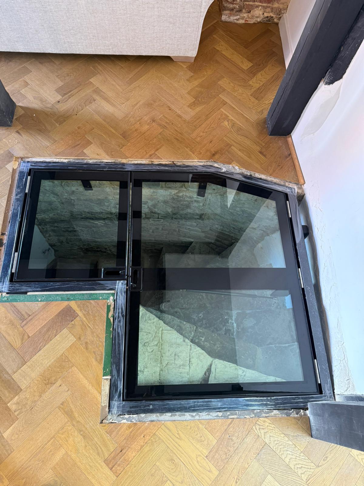 Overhead view of L-shaped hinged glass floor double door system closed, herringbone parquet, Burwash East Sussex